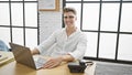 Happy and confident, young caucasian man working on his laptop in an indoor office workplace