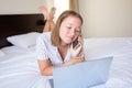 Happy confident young woman with a friendly smile lying relaxing in bed with her laptop computer Royalty Free Stock Photo