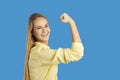 Happy confident young woman smiling and flexing her arm isolated on blue background Royalty Free Stock Photo