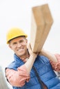 Happy Construction Worker Carrying Wooden Plank