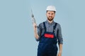 Happy construction worker in a white helmet and blue overalls with a hand drill Royalty Free Stock Photo