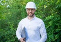 Happy constructor man in hardhat holding laptop outdoors