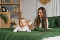 Happy and contented mother is resting on the bed with her baby son . Motherhood Royalty Free Stock Photo