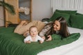 Happy and contented mother is resting on the bed with her baby son . Motherhood Royalty Free Stock Photo