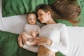 Happy and contented mother is resting on the bed with her baby son . Motherhood Royalty Free Stock Photo