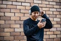 A happy, cool Asian man is using his phone and listening to music on his headphones on the street Royalty Free Stock Photo