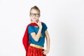 Happy and cool blond supergirl with glasses and red robe und blue shirt is posing in the studio Royalty Free Stock Photo