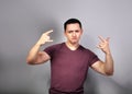 Happy cool young man showing rock sign by two hands on grey background