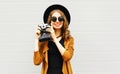 Happy cool young woman model with retro film camera wearing a elegant hat, brown jacket