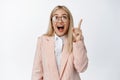 Happy corporate woman, ceo manager pointing and looking up, smiling amazed, checking out big announcement on top, white Royalty Free Stock Photo