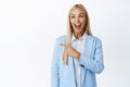 Happy corporate woman pointing and looking left, laughing and smiling enthusiastic about big promo news, standing over Royalty Free Stock Photo