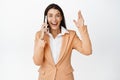 Happy corporate woman receive good news on phone call, rejoicing while talking on smartphone, standing over white Royalty Free Stock Photo