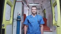 Man in medical uniform stand on the background of ambulance car.