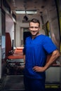 Happy corpsman stands with a smile over the ambulance car on the background