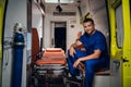 Happy corpsman in uniform sits in the ambulance car on the background