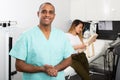 Happy cosmetologist in aesthetic medicine office with female client on background