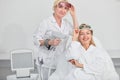 Happy cosmetologist holding laser tool and female client looking at the camera