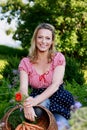 Happy countrywoman with a basket with carrots in her garden