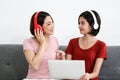 Happy Couple  asia woman wear headphones and enjoy musics playing mobile phone and tablet in bedroom Royalty Free Stock Photo