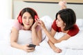 Happy Couple  asia woman wear headphones and enjoy musics playing mobile phone and tablet in bedroom Royalty Free Stock Photo