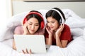 Happy Couple  asia woman wear headphones and enjoy musics playing mobile phone and tablet in bedroom Royalty Free Stock Photo