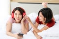 Happy Couple  asia woman wear headphones and enjoy musics playing mobile phone and tablet in bedroom Royalty Free Stock Photo