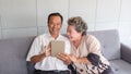 Happy couple asian senior retired using mobile tablet application technology for social network among friends community via