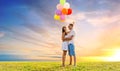 Happy couple with balloons over sunset sky Royalty Free Stock Photo