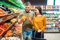 Happy couple with basket in grocery store Royalty Free Stock Photo