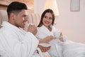 Couple in bathrobes with coffee on bed at home Royalty Free Stock Photo