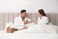 Happy couple in bathrobes with glasses of water on bed at home Royalty Free Stock Photo