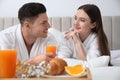 Happy couple in bathrobes having breakfast on bed Royalty Free Stock Photo