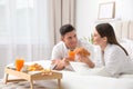 Happy couple in bathrobes having breakfast on bed Royalty Free Stock Photo
