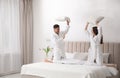 Happy couple in bathrobes having pillow fight on bed Royalty Free Stock Photo