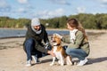 Happy couple with beagle dog on autumn beach Royalty Free Stock Photo