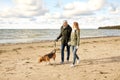 Happy couple with beagle dog on autumn beach Royalty Free Stock Photo