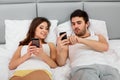 Happy Couple in a Bed with Mobile Phones Royalty Free Stock Photo