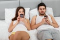 Happy Couple in a Bed with Mobile Phones Royalty Free Stock Photo