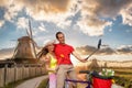 Happy couple on bike against traditional Dutch windmills in Zaanse Schans, Amsterdam area, Holland