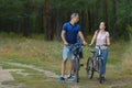 Happy couple with bikes in park, cycling at summer day. Royalty Free Stock Photo