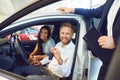 A happy couple bought a new car at a car showroom.