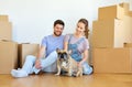 Happy couple with boxes and dog moving to new home Royalty Free Stock Photo