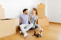 Happy couple with boxes and dog moving to new home Royalty Free Stock Photo