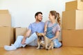 Happy couple with boxes and dog moving to new home Royalty Free Stock Photo