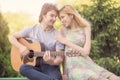 Happy couple, boyfriend playing guitar for his girlfriend