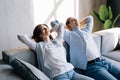 Happy couple breathing and resting lying in a couch at home with a window in the background Royalty Free Stock Photo