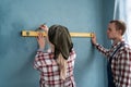 Happy couple building new home measuring wall using spirit level to measure. Repair, building and home concept Royalty Free Stock Photo