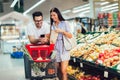 Couple buying vegetables at grocery store or supermarket using smart phone - shopping, food, sale, consumerism