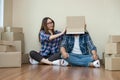 Happy couple with cardboard boxes on their heads sitting on floor after the moving house. Royalty Free Stock Photo