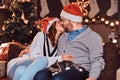 Happy couple celebrating Christmas Eve at home kiss while sitting on sofa. Christmas holiday. Royalty Free Stock Photo